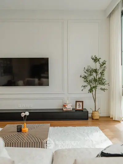 Modern living room with stylish decor and large TV on wall.