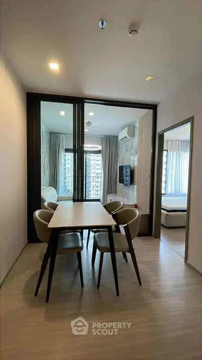 Modern dining area with sleek table and chairs, adjacent to a cozy living room with city view.