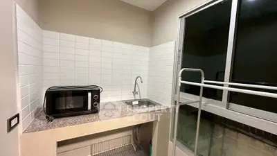 Compact kitchen with microwave and sink, featuring a sliding glass door for natural light.