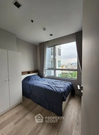 Cozy bedroom with large window and modern decor in urban apartment