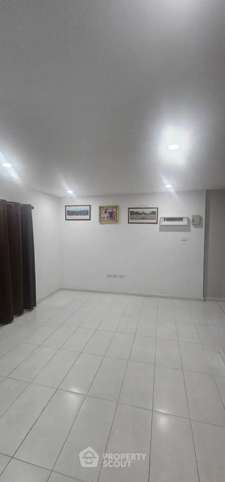 Spacious empty room with tiled flooring and wall art, ideal for customization.