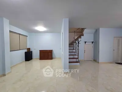 Spacious open-plan living area with modern staircase and tiled flooring