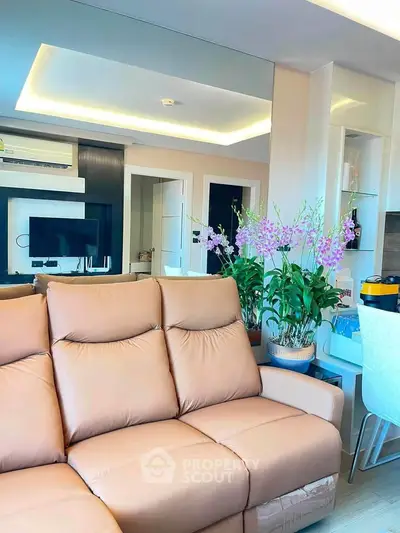 Modern living room with plush sofa and elegant decor, featuring built-in shelves and stylish lighting.