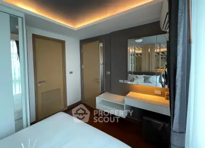 Modern bedroom with sleek design, featuring a mirrored wardrobe and stylish lighting.