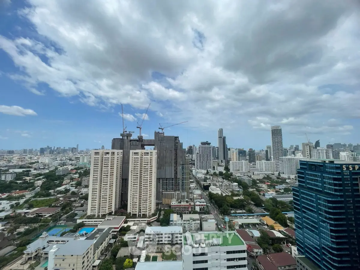 Stunning cityscape view showcasing high-rise buildings under a vibrant blue sky with scattered clouds.