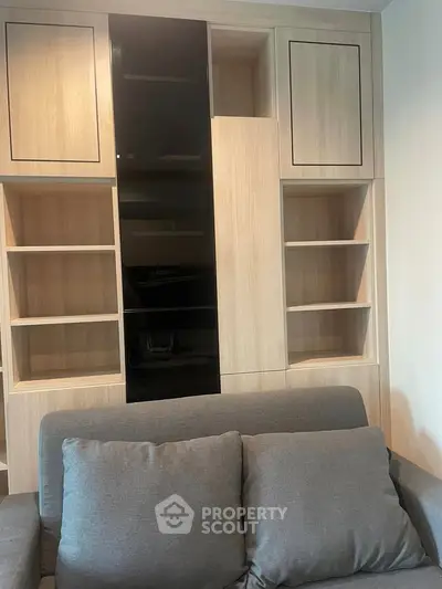 Modern living room with stylish built-in wooden shelving and comfortable gray sofa.