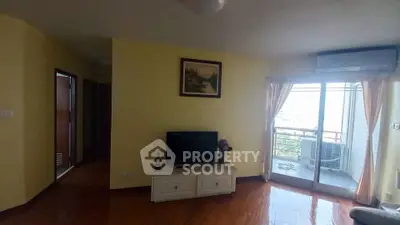 Cozy living room with TV and balcony access, featuring wooden flooring and natural light.