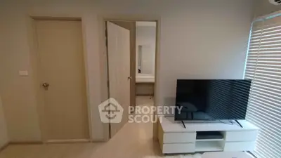 Modern living room with sleek TV setup and natural light from blinds.