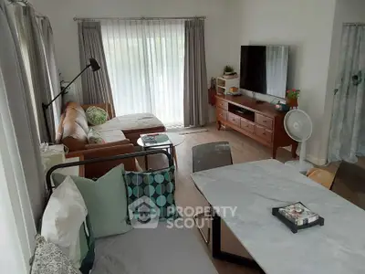 Spacious living room with modern decor, featuring a cozy sofa, stylish dining table, and large windows for natural light.