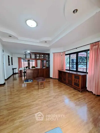 Spacious living room with wooden flooring and large windows for natural light.