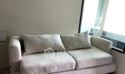 Modern minimalist living room with cozy white sofa and large window.