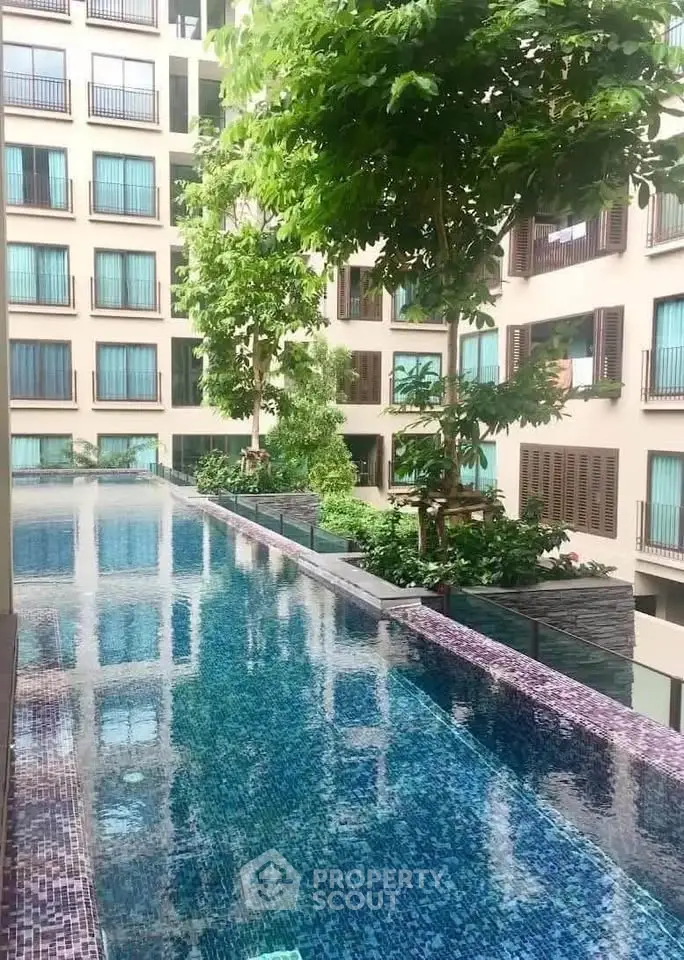 Luxurious apartment complex with stunning pool and lush greenery.