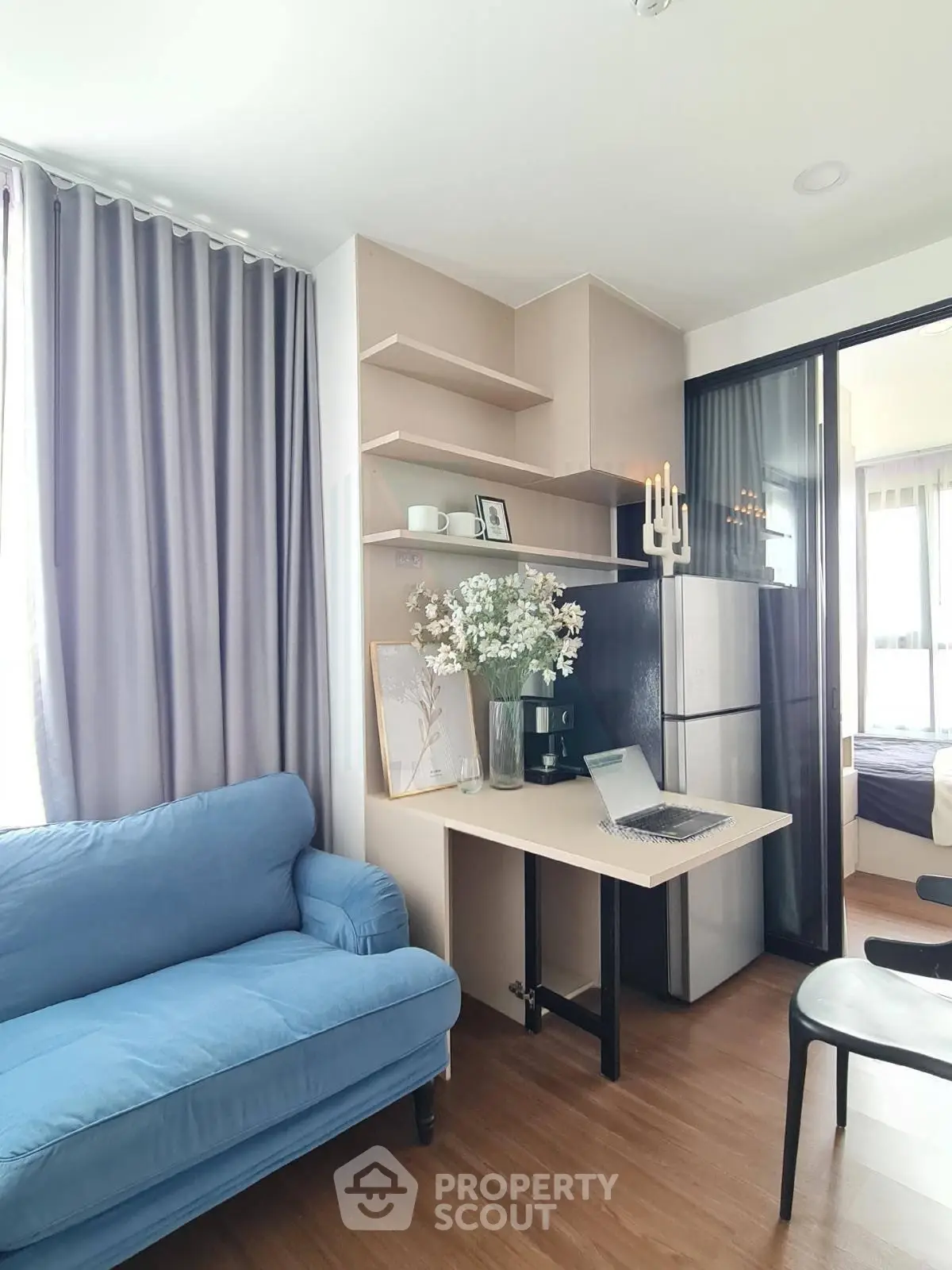 Modern living room with blue sofa, stylish shelving, and natural light for a cozy ambiance.