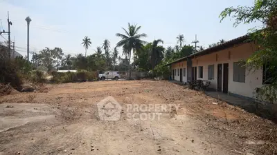 Spacious land plot with potential for development, featuring a single-story building and tropical surroundings.