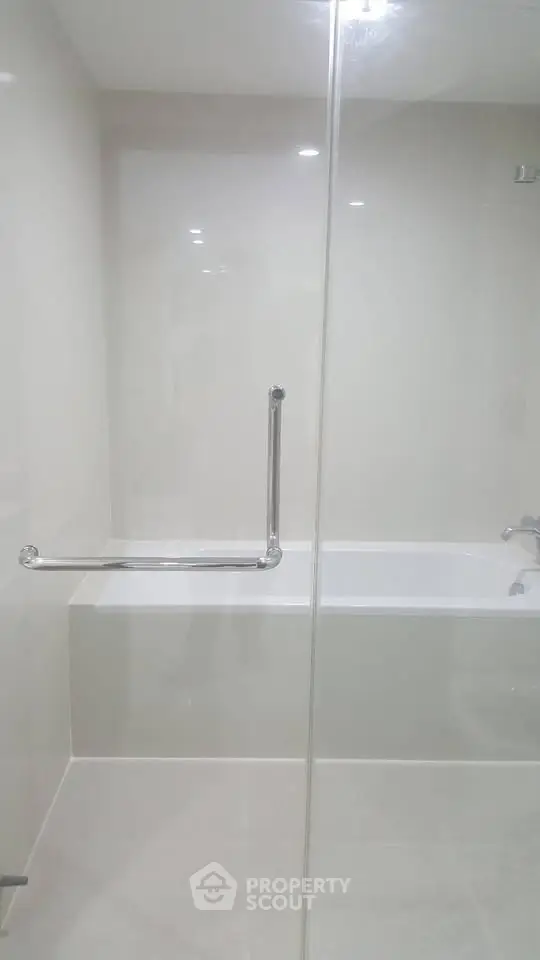 Modern bathroom with sleek bathtub and glass partition in a minimalist design.