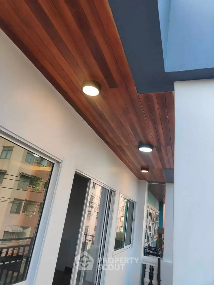 Stylish balcony with wooden ceiling and modern lighting in contemporary apartment building.