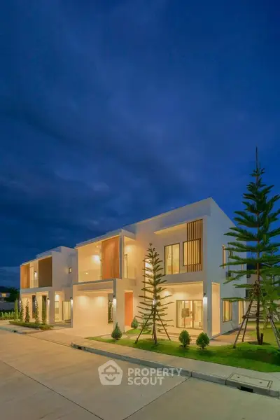 Modern two-story homes with sleek design and ambient lighting at dusk, showcasing contemporary architecture.