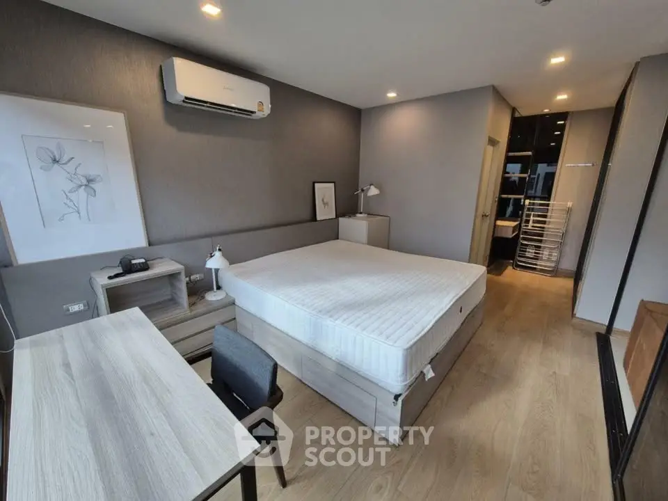 Modern bedroom with minimalist decor, featuring a comfortable bed, desk, and air conditioning unit.