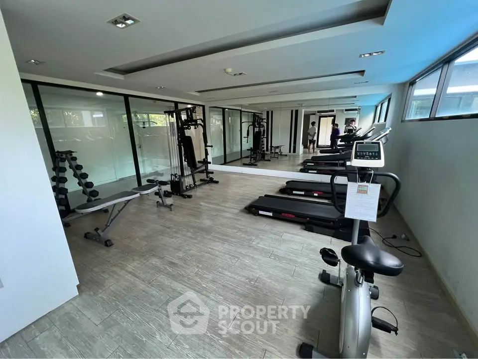 Modern gym with state-of-the-art equipment and large mirrors in a luxury residential building.