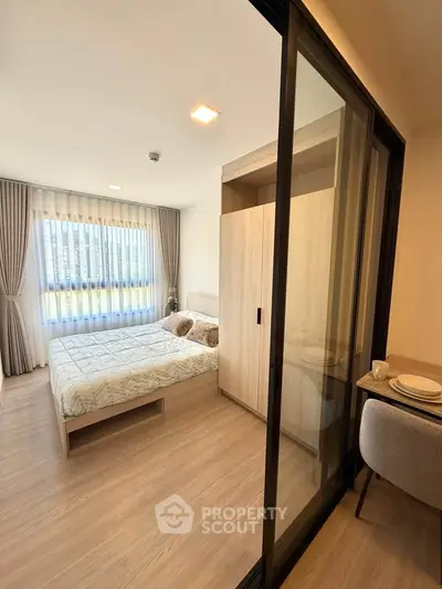 Modern bedroom with large window and sliding glass door, featuring stylish decor and ample natural light.