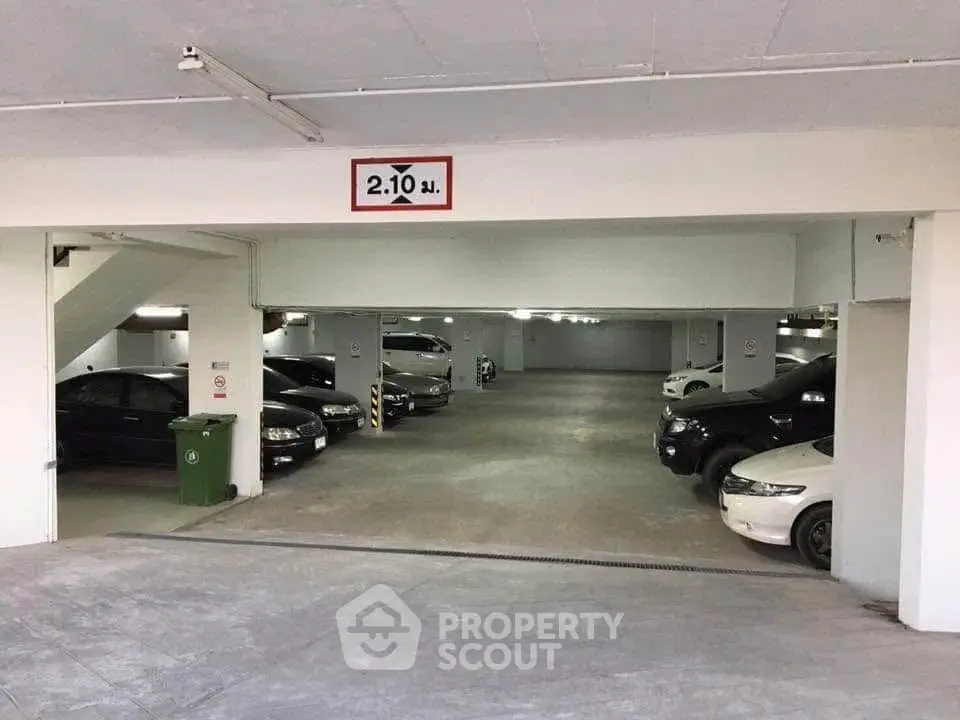 Spacious underground parking area with multiple cars and clear height signage.