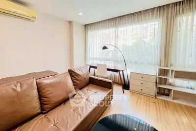 Modern living room with brown leather sofa and large window for natural light.