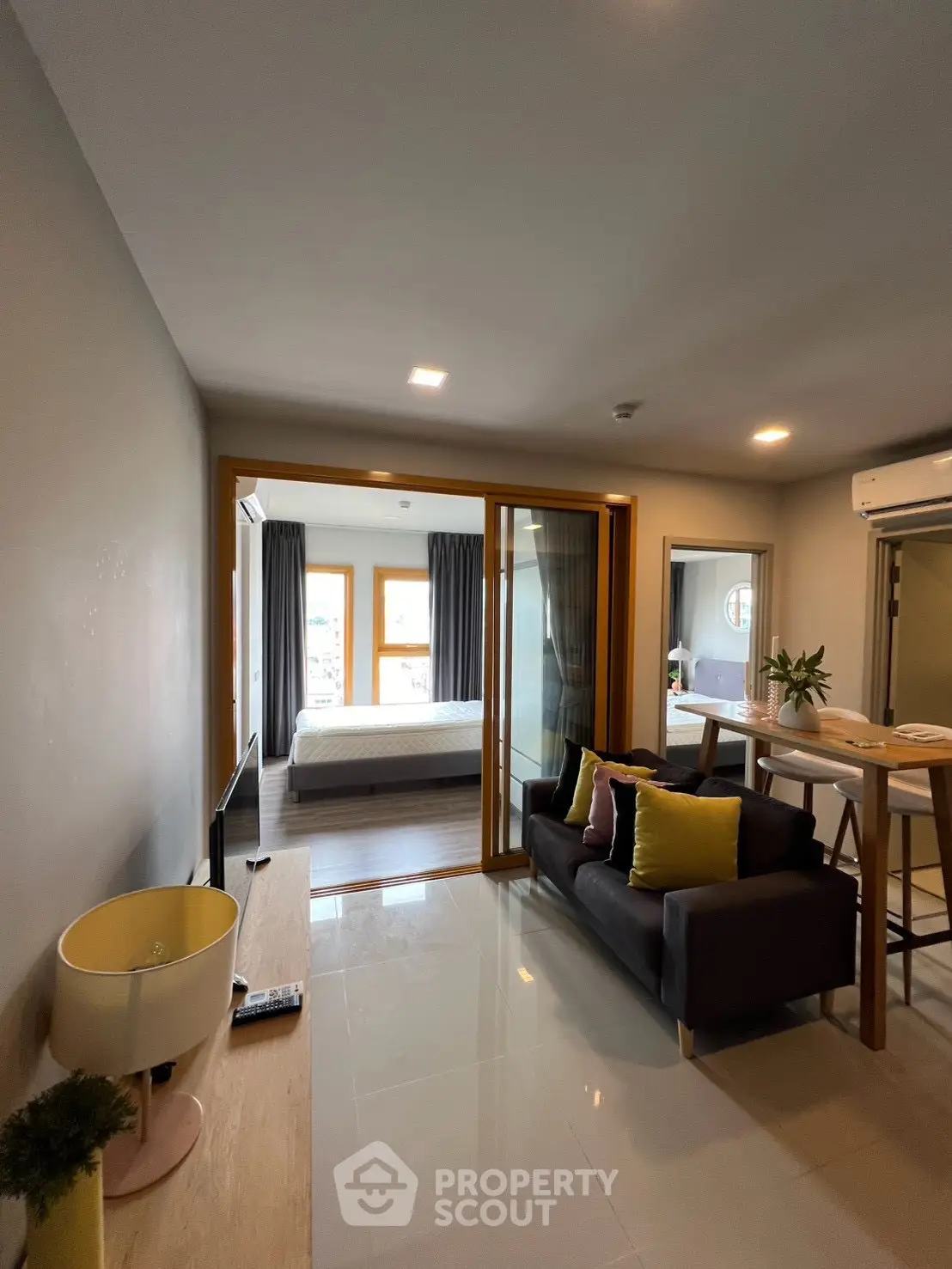 Modern living room with open layout leading to a cozy bedroom, featuring stylish decor and ample natural light.