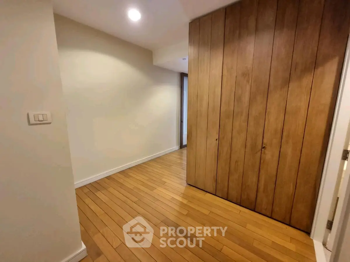 Spacious hallway with wooden flooring and built-in storage cabinets.