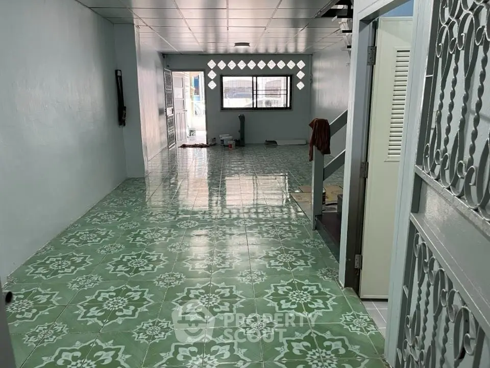 Spacious interior with patterned green floor tiles and ample natural light.