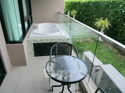 Charming balcony with jacuzzi and garden view, perfect for relaxation and outdoor dining.