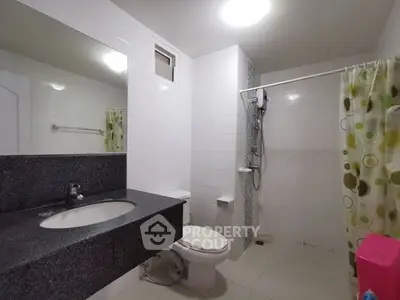 Modern bathroom with sleek countertop and shower area in a contemporary home.