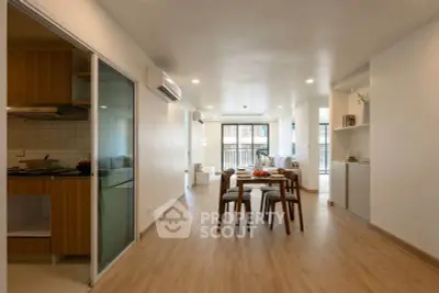 Spacious modern living room with open layout and elegant dining area, featuring wooden flooring and ample natural light.