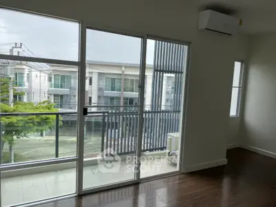 Modern apartment with large windows and balcony offering a serene view of the neighborhood.