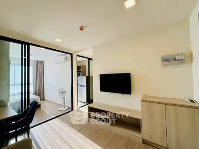 Modern living room with sleek design and natural light, featuring a wall-mounted TV and stylish furniture.