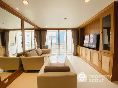 Spacious living room with elegant wooden cabinetry and large windows offering an urban view, complemented by modern furnishings.