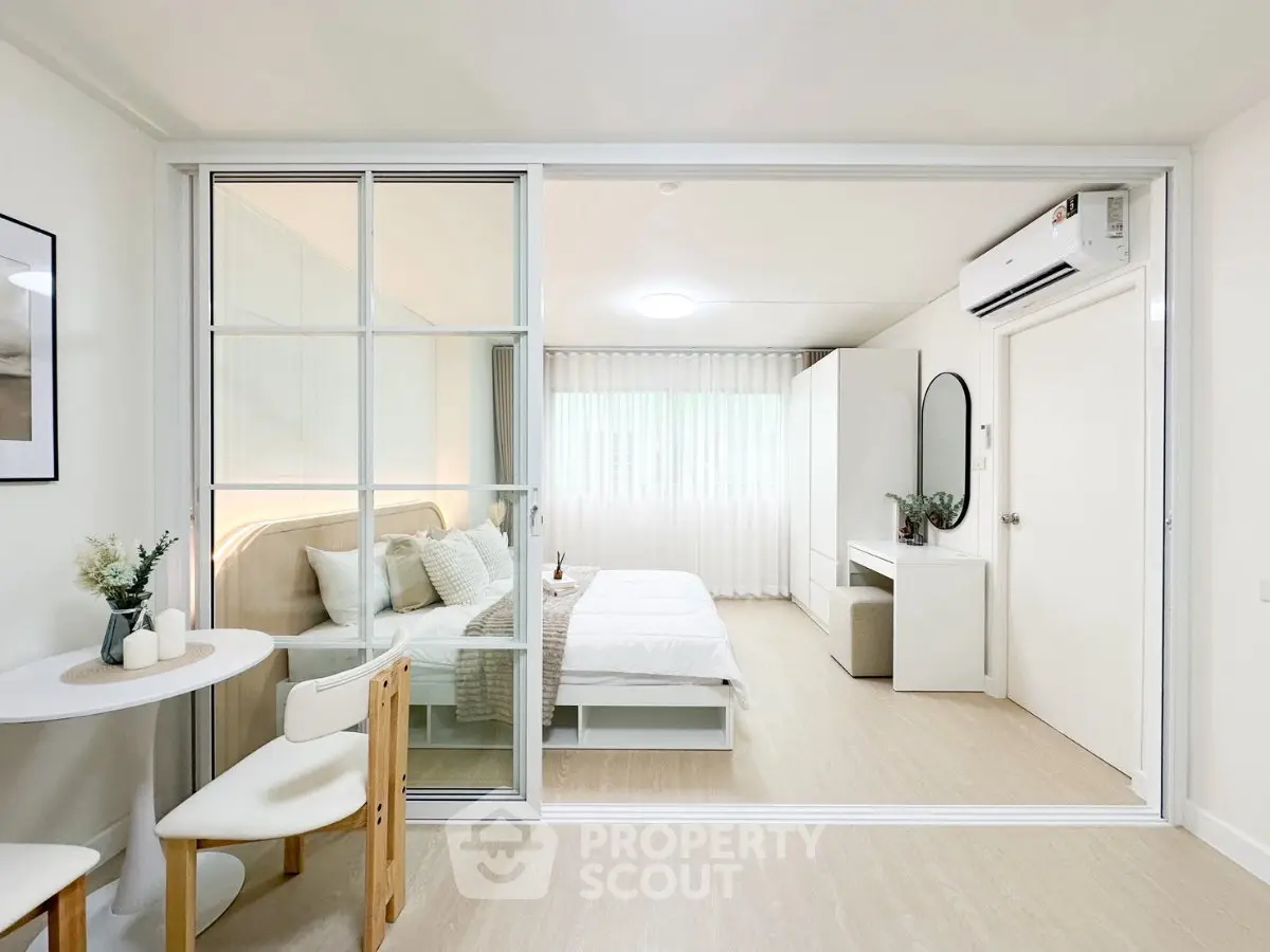 Modern bedroom with glass partition and minimalist decor in a bright apartment.