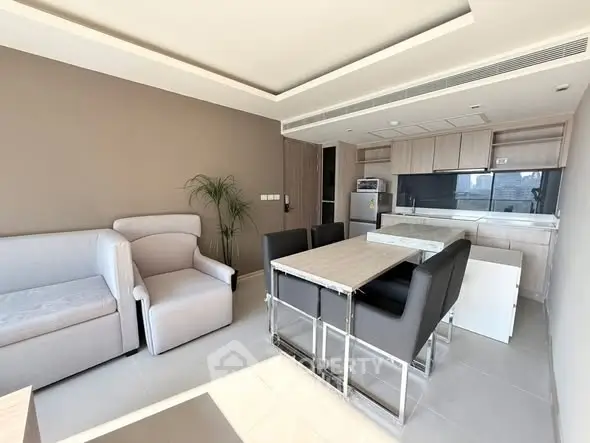 Modern open-layout living room with sleek kitchen and dining area, featuring contemporary furniture.