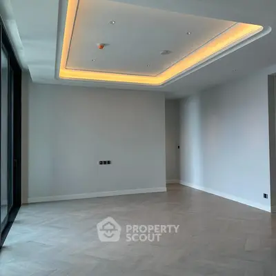 Spacious modern living room with elegant ceiling lighting and large windows.