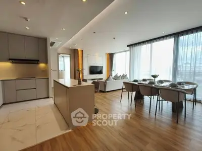 Spacious open-plan living and dining area with modern kitchen in luxury apartment.
