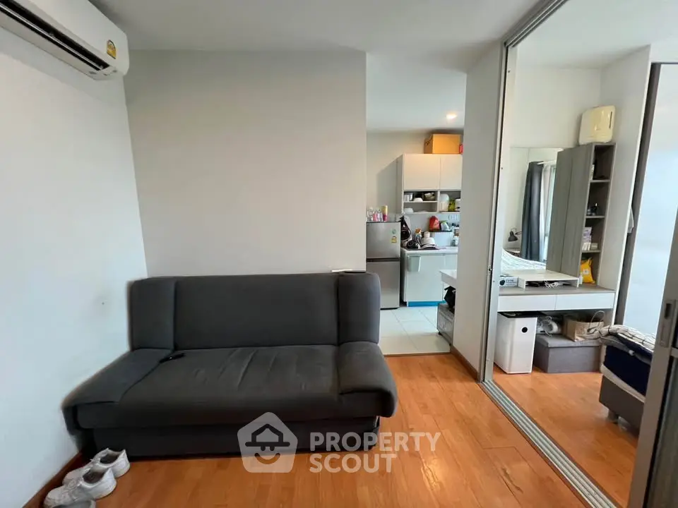 Modern living room with sleek sofa and open kitchen layout in a cozy apartment.