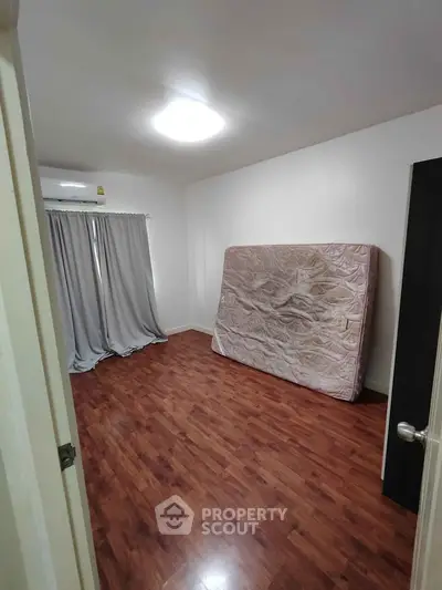 Spacious empty bedroom with wooden flooring and natural light, ready for customization.
