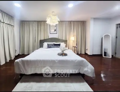 Spacious bedroom with elegant decor and wooden flooring, featuring a cozy bed and ambient lighting.