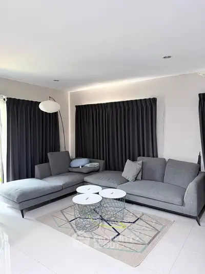 Modern living room with stylish gray sofas and chic coffee tables on a geometric rug.