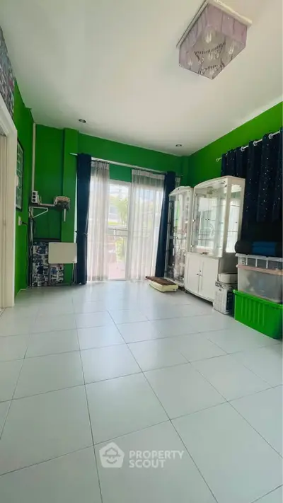 Spacious living room with vibrant green walls and large windows for natural light.