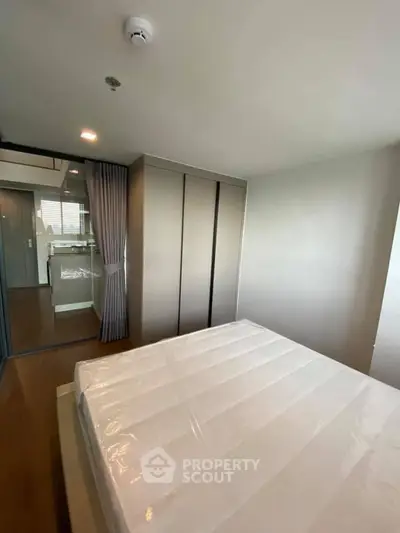 Modern bedroom with sleek closet and view into stylish kitchen area