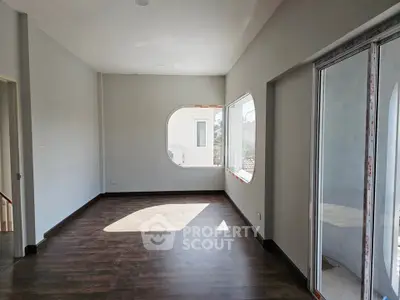 Spacious living room with unique window design and wooden flooring