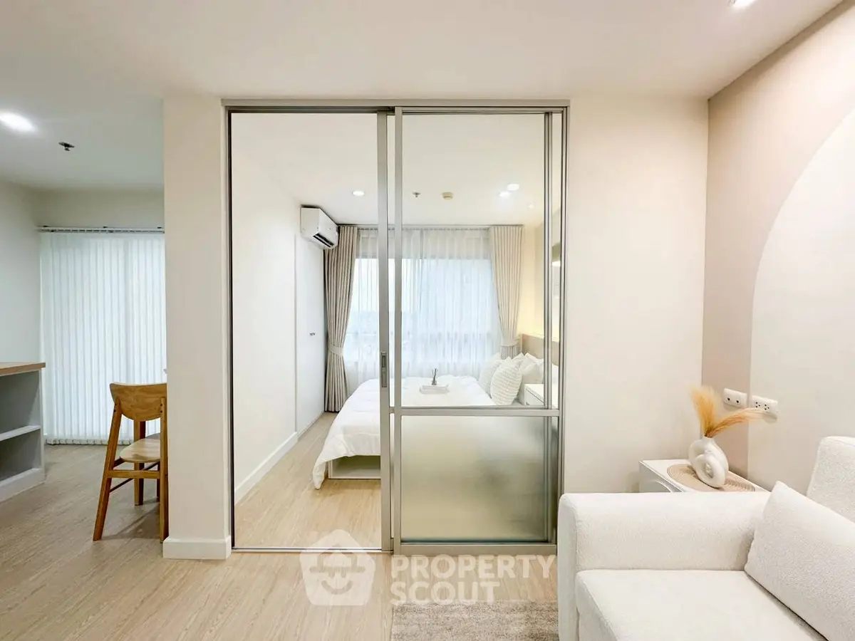 Modern living room with sliding glass doors leading to a cozy bedroom