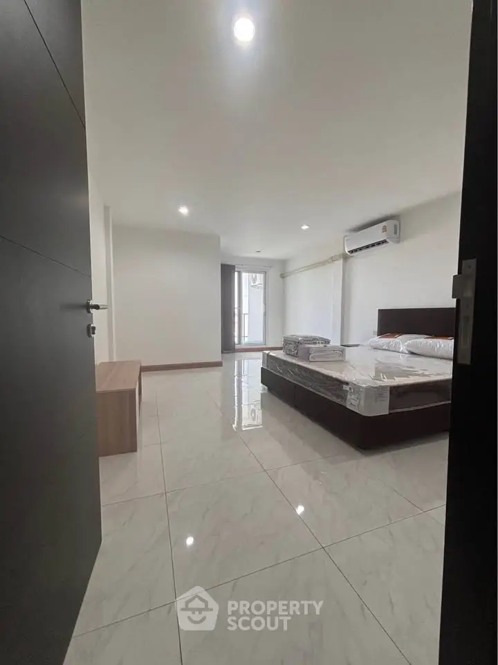 Spacious modern bedroom with sleek tile flooring and natural light