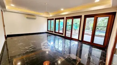 Spacious living room with marble flooring and large windows overlooking garden