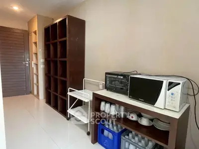 Modern kitchen area with microwave and storage shelves in a sleek apartment